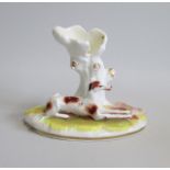 A Staffordshire porcelain Greyhound and Hare Spill holder, the greyhound laying on a green grassy