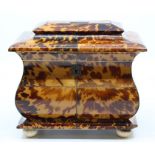 A George III tortoiseshell sarcophagus shaped tea caddy, enclosing two lidded compartments, on