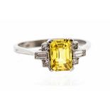 A yellow sapphire and diamond platinum ring, the emerald cut sapphire weighing approx. 1.4 carats,