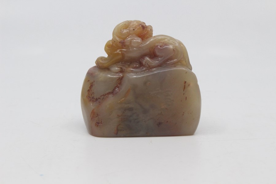 A Chinese pale green and russet jade seal, 20th Century, carved as a recumbent lion dog atop a rock, - Image 2 of 3