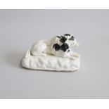 A Staffordshire Model of a Little Lion Dog with black markings laying on a white rocky base  Date: