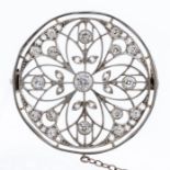A diamond and platinum set circular brooch, fine open work floral design decorated with grain set