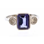 A tanzanite and diamond three stone platinum ring, the rectangular cut tanzanite weighing approx.