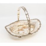 A George V silver shaped oval swing handled cake basket, recticulated sides wth cast scrolling
