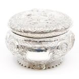 A late Victorian silver circular embossed box and cover, the cover chased with central section