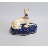 A Staffordshire Hound,  laying on a Cobalt blue ground base  with a feeding bowl or pen holder