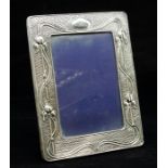 An Edwardian Art Nouveau silver photo frame, with sinuous decoration and tulip motifs on an engine