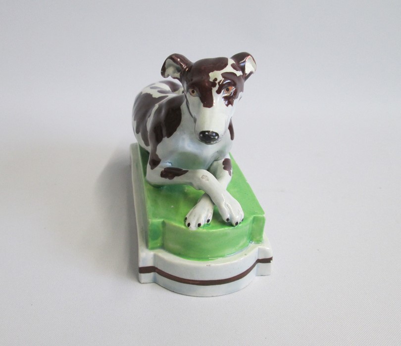 A Staffordshire model of a recumbent Greyhound/Whippet painted with brown markings, laying on a - Image 3 of 6