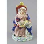 An early nineteenth century Staffordshire pearlware figure of Saint Anne, c.1810-20. She is seated