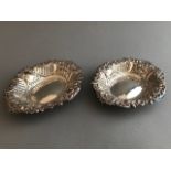 A pair of embossed silver oval trinket dishes with trellis, floral and scroll design, marks