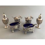 A pair of George V pierced oval silver salts, with blue glass liners on ball and claw feet, London