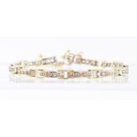 A two colour 18ct gold diamond bracelet of twelve rectangular links, each channel set five brilliant