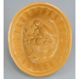 An early nineteenth century yellow-glazed jelly mould, c. 1820. It depicts a parrot sitting on a