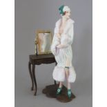An Albany Fine China Co. model of a lady standing next to a dressing table, incorporating a metal