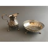 A George II silver cream jug with later bird and fruit embossing, on shaped feet, London 1748 and