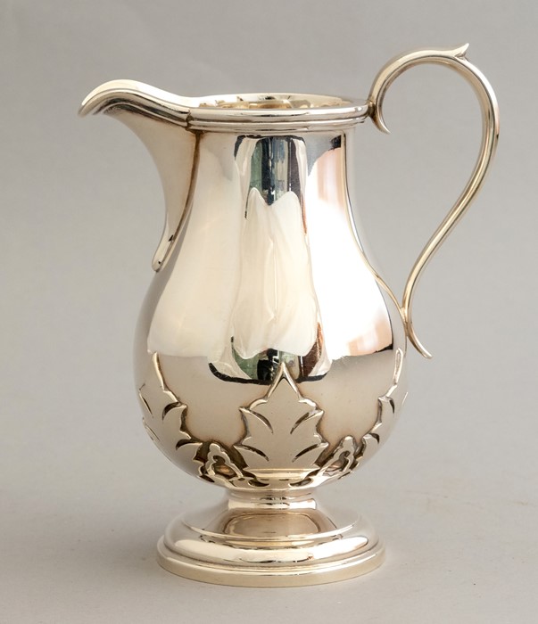 A George VI silver milk jug, scroll handle, thistle leaf frieze, baluster body, maker Edward & Sons,