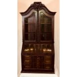 An early 18th Century walnut apprentice glazed bookcase on bureau, arch shaped cornice with a