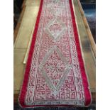 A long intricate designed Middle Eastern sideboard cloth in a red design on a woven background, with