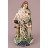 An early nineteenth century Staffordshire pearlware figure of Charity, c.1810-20. She is standing