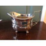 A George III silver boat shape milk jug with leaf engraved frieze, gadroon rim on ball feet,