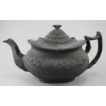 An early nineteenth century black basalt teapot, c.1810-20. It is of moulded form decorated with