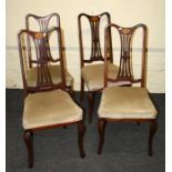 A set of four Edwardian mahogany dining chairs, each having fan inlaid rail, pierced waisted