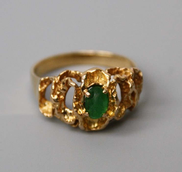 A single stone emerald ring, the oval emerald in pierced undulating mount. 5.7g, stone scuffed and