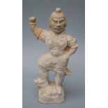 An old Chinese un-glazed pottery tomb type figure of a Lokapala with arm raised and fierce