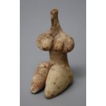 An archaic form pottery female fertility figure of with large thighs and pendulous breasts but