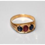 A three stone sapphire and ruby half hoop ring, the oval cut stones in flush carved mount within a