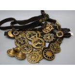 A collection of fourteen largely early 20th Century horse brasses suspended from four martingales,