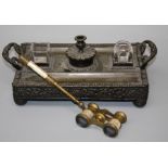 A late 19th century brass desk stand with two wells, pen trays and candle holder, decorated in