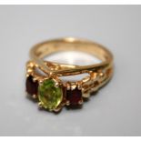 A peridot and garnet three stone half hoop ring, , the slightly graduated oval stones in pierced and