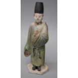 An old Chinese green glazed and poly-chromatic painted tomb type figure of an attendant with tall