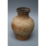 An old Chinese terracotta, funerary wine jar of heavy baluster form with remnants of incised and