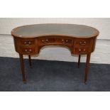 An Edwardian inlaid mahogany kidney shaped, lady's writing desk with inset leather top over two