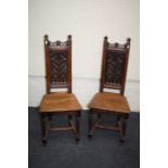 A pair of probably French gothic carved oak hall chairs with tracery backs raised on turned