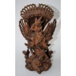 A Balinese carved hardwood figure of Garuda swooping upon a sea creature. Marked "Nyomansetter,