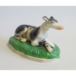 Staffordshire Model of a recumbent Greyhound on a Green Base Date   1860 Size  15.5 cm diam   9cm
