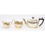An Edwardian three piece teaservice, fluted bodies, the teapot with ebony handle and pagoda finial