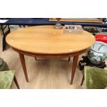A 1970's oval teak dining table, in the G Plan style, raised on tapered legs, the table forming a