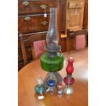 A late 19th Century brass and green glass oil lamp, a small red coloured standing oil lamp, a