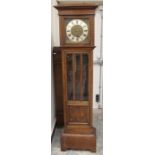 An early 20th Century oak Grandmother clock, the face with a silvered chapter dial and black Roman