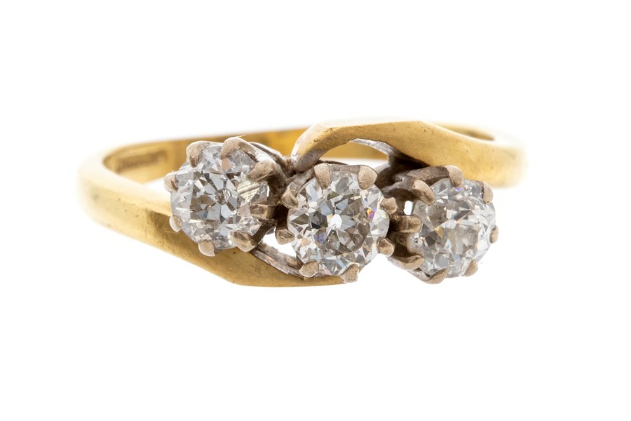 A three stone diamond 18ct gold cross over ring, comprising three claw set old cut diamonds with a