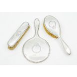 A George V matched three piece silver dressing table set, compring mirror and two brushes, reeded
