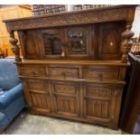 A Jacobean style oak court cupboard, two glazed doors to top, cup and cover supports, the base