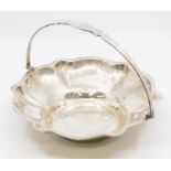 A George V silver shaped circular basket, wavy border above lobed sections, swing handle, by