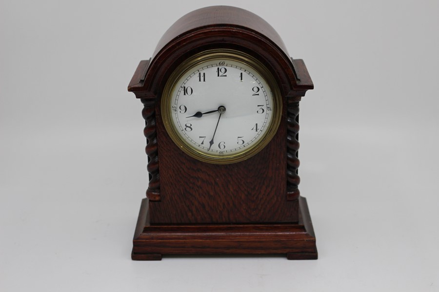 Two early 20th Century French mantel clocks, the first of barrel form on scroll base in ebonised