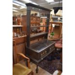 An early 20th Century Jacobean Style oak kitchen dresser, with plate rack, two drawers, with brass