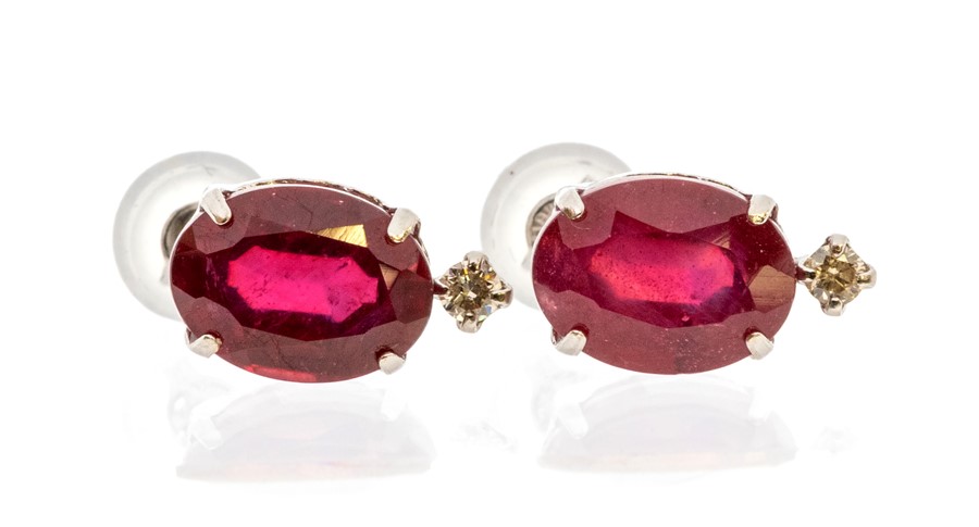 A pair of ruby and diamond 18ct white gold earrings, comprising faceted oval rubies claw set with